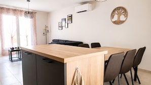 Una cocina moderna con una isla de madera, armarios negros y un comedor con sillas.