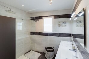 A modern bathroom with a shower, a sink, and a large mirror.