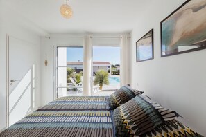 A bedroom with a bed, a door, and a view of a pool and outdoor seating. - Villa Tikaz 4* Ile d'Oléron 8 people swimming pool (Saint-Denis-d'Oléron)