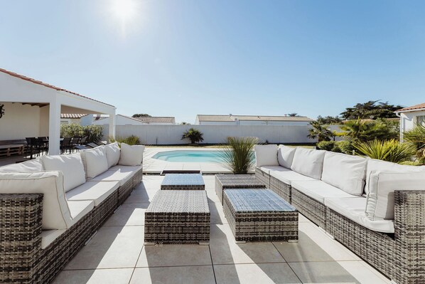 A rooftop patio with a pool, outdoor furniture, and a clear sky.