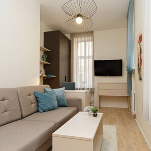 A modern living room with a sofa, coffee table, and a flat-screen TV mounted on the wall. - Bright, stylish studio in center (Riga)