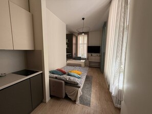 A compact bedroom with a bed, bedside table, and a desk area. - Bright, stylish studio in center (Riga)