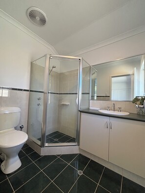 A bathroom with a glass-enclosed shower, a toilet, a sink, and a mirror. - 3 Bed Home Near Crown, City, Optus & Airport (Carlisle)