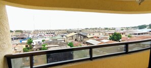 Une vue depuis un balcon donnant sur un paysage urbain, avec des bâtiments, un pont et une étendue d’eau.
