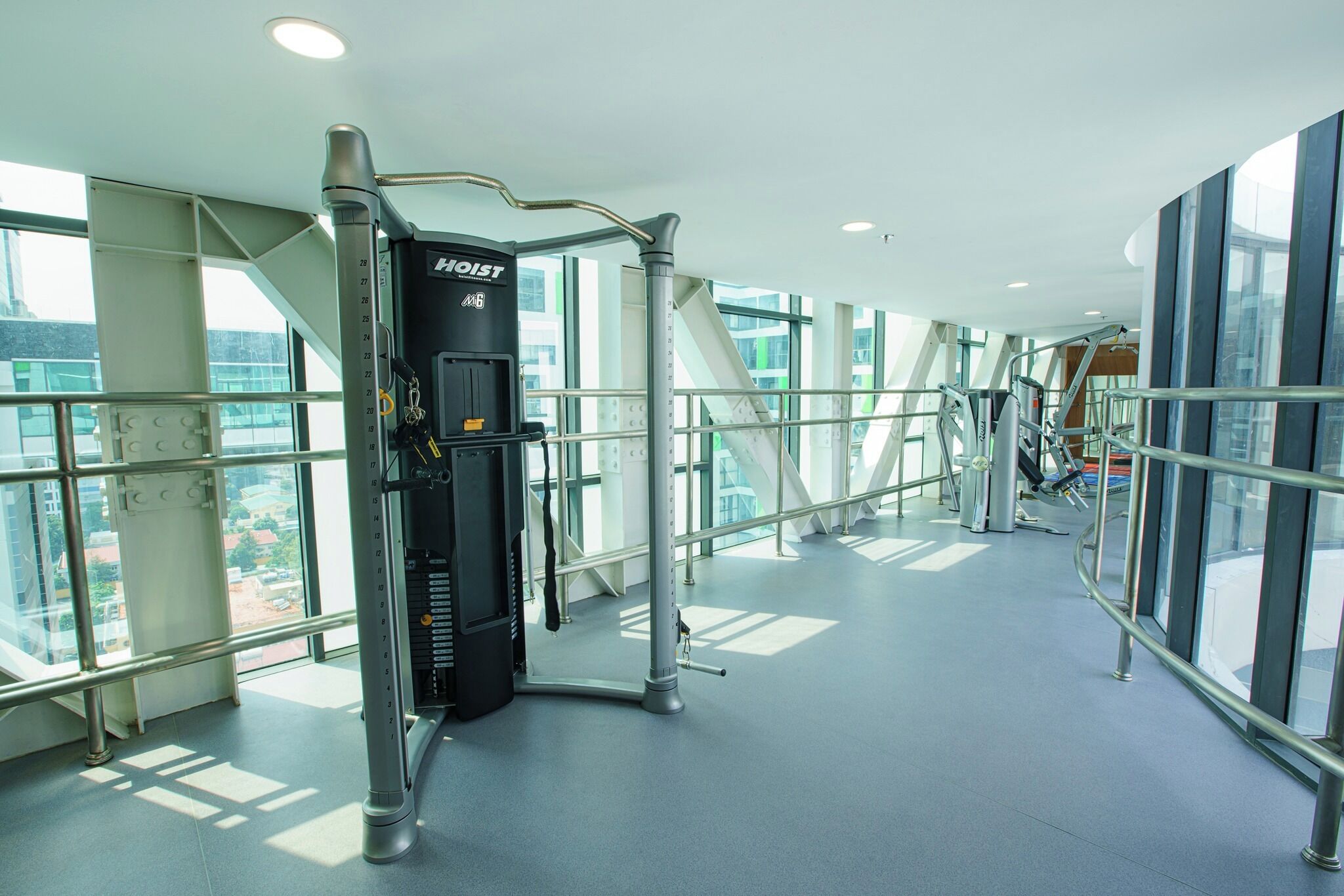 A gym with a stationary bike, a wall-mounted exercise machine, and a staircase.