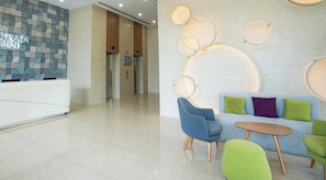 A modern reception area with a check-in counter, elevators, and a seating area with a sofa and chairs. - Republic Plaza TSN Airport Emily in Town (Ho Chi Minh)