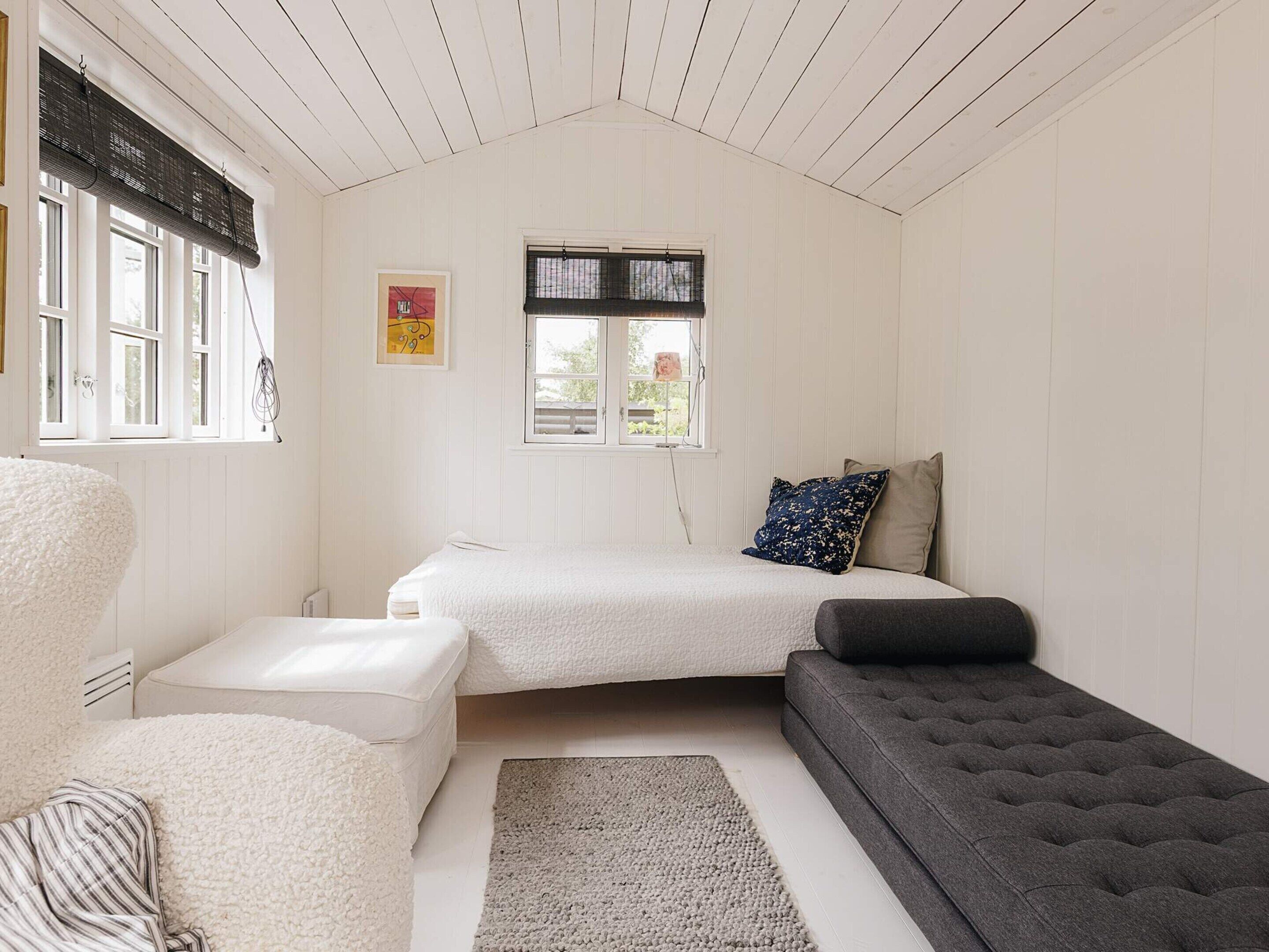 Una habitación con una cama, un sofá, una silla y una ventana con persianas.