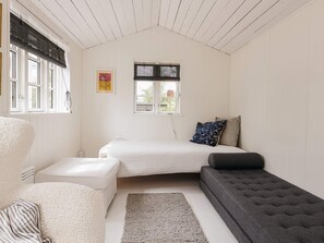Una habitación con una cama, un sofá, una silla y una ventana con persianas.