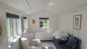 A cozy room with a bed, a sofa, a chair, a small table, and a lamp. - 2 Person Holiday Home in Dannemare (Dannemare)