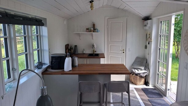 A compact kitchen with a wooden countertop, two bar stools, a kettle, and a coffee machine. - 2 Person Holiday Home in Dannemare (Dannemare)