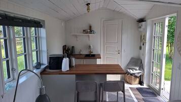 Cozinha compacta com bancada de madeira, dois banquetes, chaleira e máquina de café.