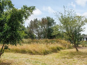 A natural landscape with trees, grass, and a building in the background. - 2 Person Holiday Home in Dannemare (Dannemare)
