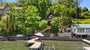 Ein Steg mit einer Leiter, einem Boot und einem Haus mit einem Balkon mit Blick auf ein Gewässer.