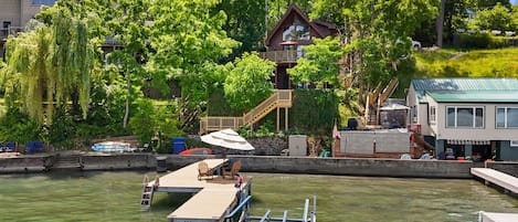 Un muelle con una escalera, un barco y una casa con balcón que da a un cuerpo de agua.