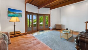 Ein Zimmer mit Bett, Lampe, Tisch und Blick durch eine Glastür.