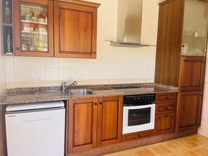 A kitchen with wooden cabinets, a stainless steel sink, a built-in oven, and a dishwasher.