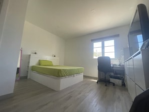 Ein Schlafzimmer mit einem Bett, einem Schreibtisch und einem Fenster.