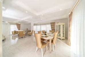 A spacious dining area with a round table, multiple chairs, and a cabinet with glass doors.