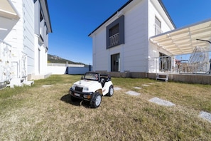 A white building with a covered patio area and a small white car parked on the grass.