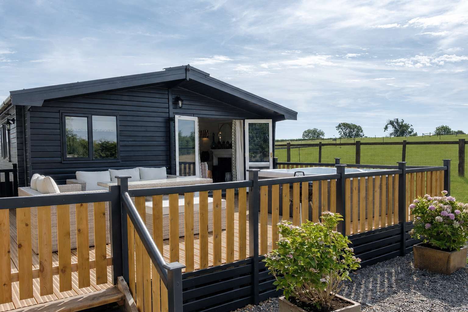 Une cabane moderne dotée d’une terrasse, d’une cheminée et offrant une vue sur le paysage environnant.