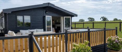 Uma cabana moderna com varanda, lareira e vista do horizonte.