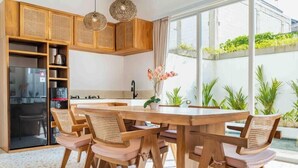 Una cocina moderna con armarios de madera, una mesa de comedor con sillas y vistas a un jardín.