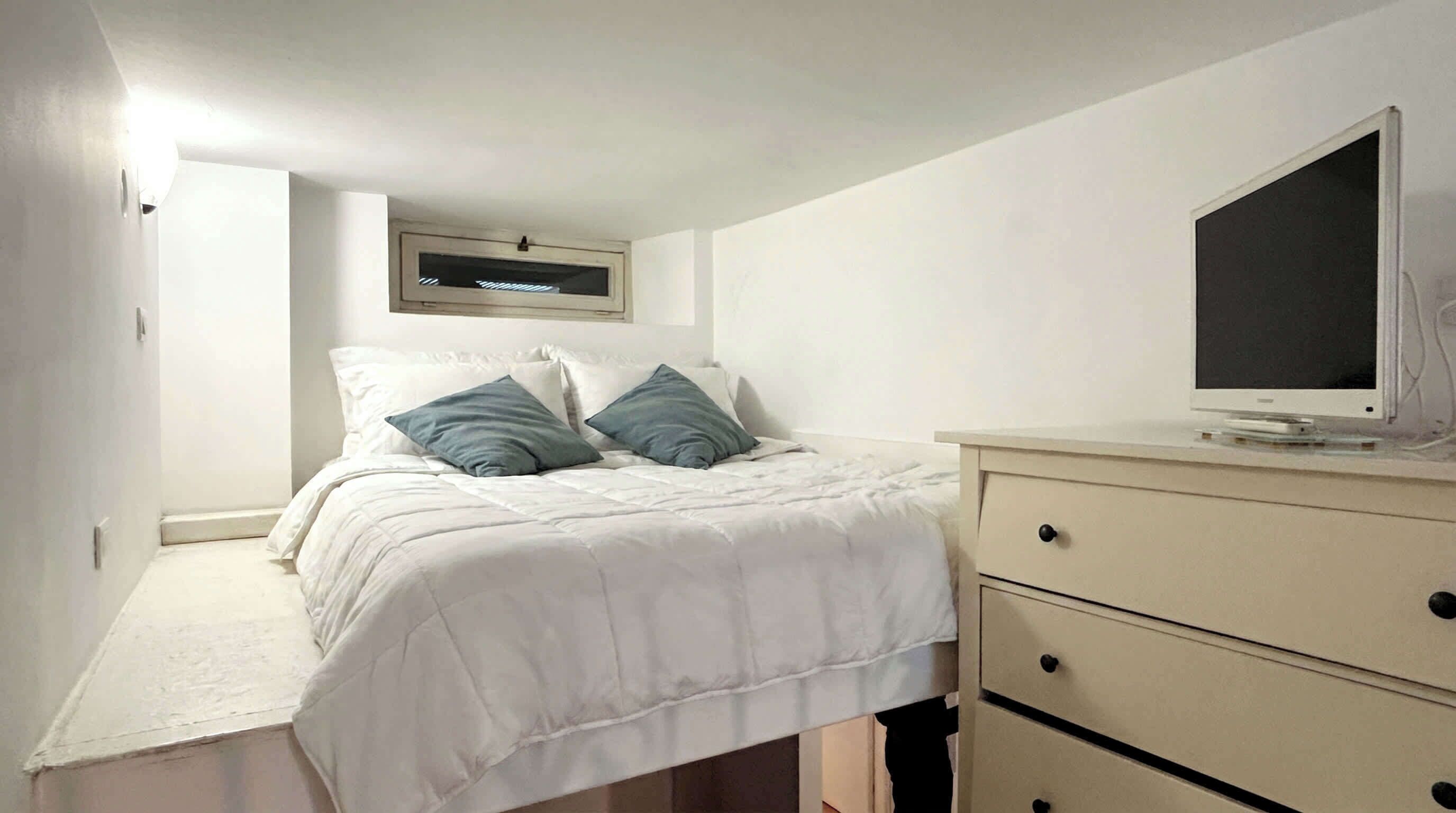A bedroom with a bed, a bedside table, a TV, and a wardrobe.