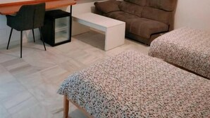 Una habitación pequeña y moderna con una cama, un escritorio, una silla y un ventanal con persianas.