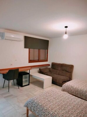 Habitació petita i moderna amb un llit, un escriptori, una cadira i una finestra amb persianes.