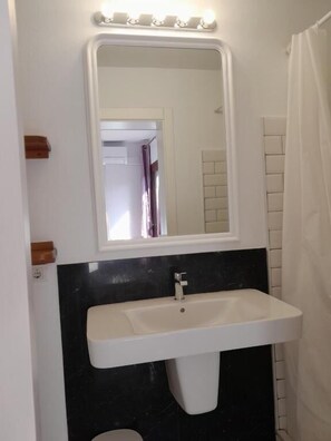 Un bany amb un lavabo blanc, un mirall amb il·luminació i un vàlida de bany.