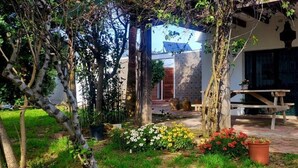 Un patio con un banco de madera, plantas en macetas y un edificio con tejado de baldosas.