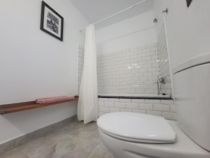 A bathroom with a white toilet, a shower with a white curtain, and a tiled wall. - La Ola Tarifa (Tarifa)