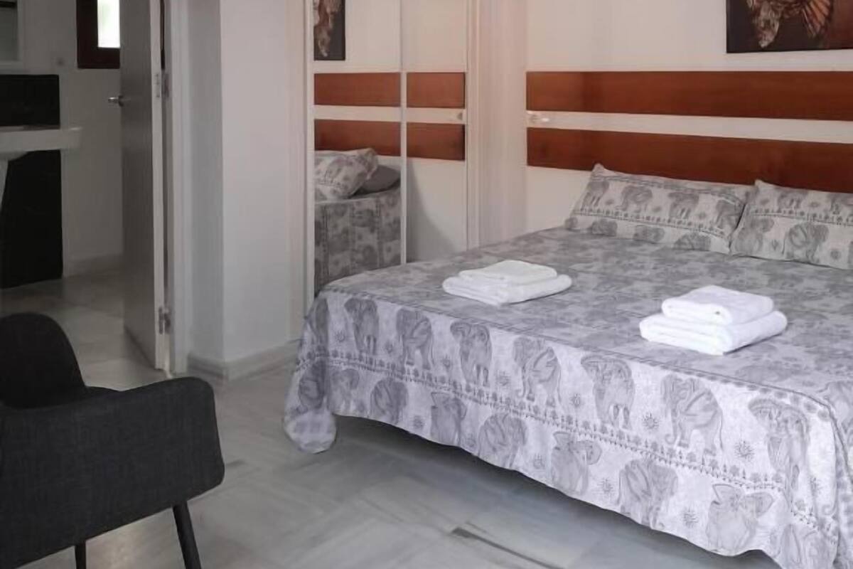 A bedroom with a bed, a chair, a wardrobe, and a painting on the wall.