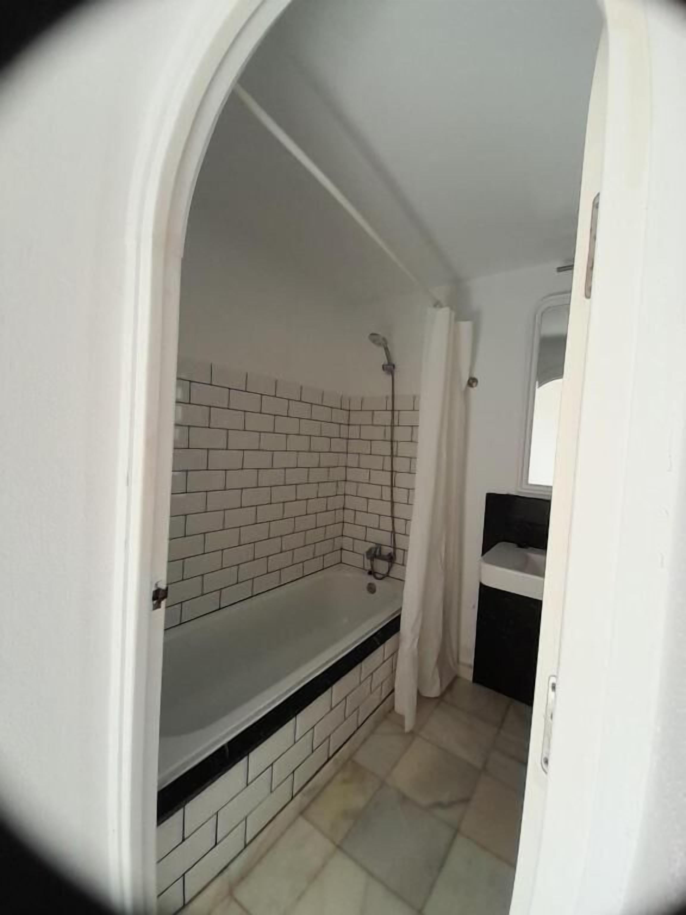 A bathroom with a bathtub, a shower, and a tiled wall.