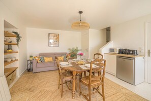 A compact living space with a dining table, chairs, a sofa, a kitchen area, and a staircase. - Le Clos Vinzelles - House + outbuilding in the heart of the vineyards, large garden (Vinzelles)
