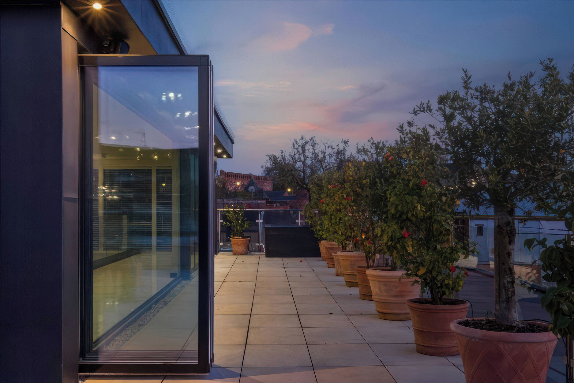 A modern building with a glass entrance, potted plants, and a clear sky.