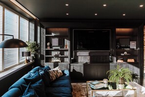 A modern living room with a dark blue sofa, a coffee table, and a TV. - Luxury two Story Penthouse With Roof top Terrace (Shrewsbury)
