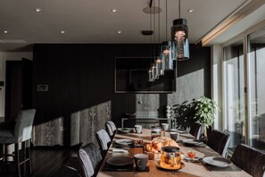 A modern dining area with a long table, chairs, and a hanging light fixture. - Luxury two Story Penthouse With Roof top Terrace (Shrewsbury)