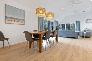 Ein modernes Wohnzimmer mit Essbereich, großen Fenstern und Deckenventilator.