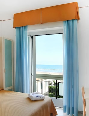 Une chambre d’hôtel avec un lit, un balcon et vue sur la plage.