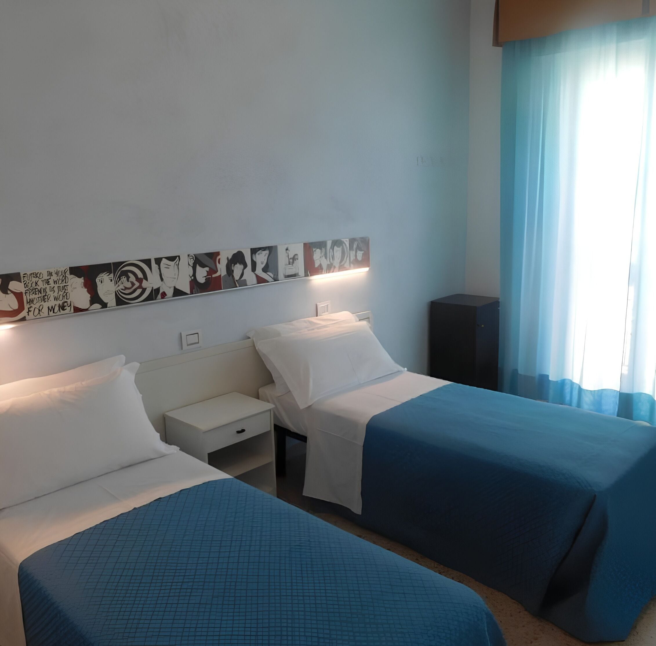 A hotel room with two beds, a nightstand, a wall-mounted artwork, and a window with curtains.