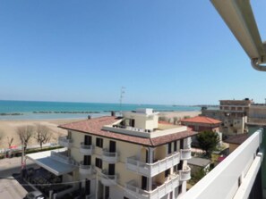 Un immeuble à plusieurs étages doté de balcons, offrant une vue sur la plage et s’ouvrant sur un ciel dégagé.