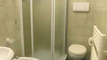 Un baño con cabina de ducha, inodoro y bidé.
