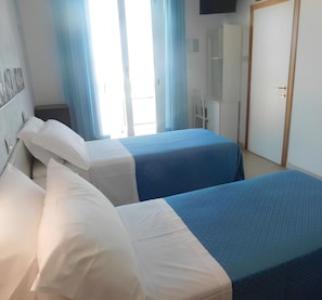 Une chambre d’hôtel avec deux lits, une télévision, une armoire et une porte.