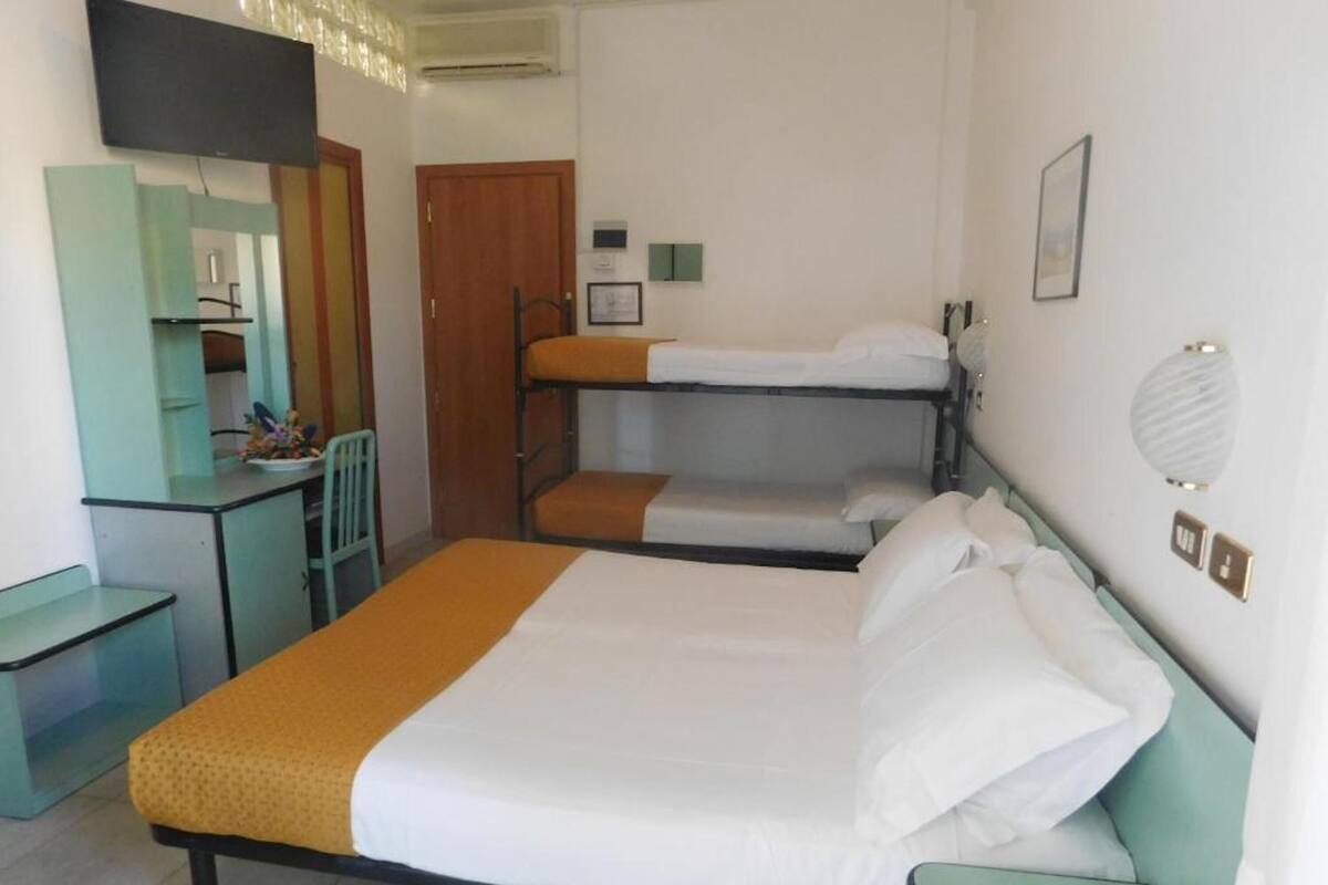 A room with a single bed, a desk, a chair, and a bunk bed.