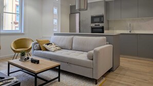 A modern living room with a sofa, a coffee table, and a kitchen area with a microwave and oven. - Paz Apartments By Como En Casa (A CORUÑA)