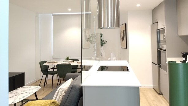 A modern kitchen with a central island, dining area with chairs, and a sofa. - Paz Apartments By Como En Casa (A CORUÑA)