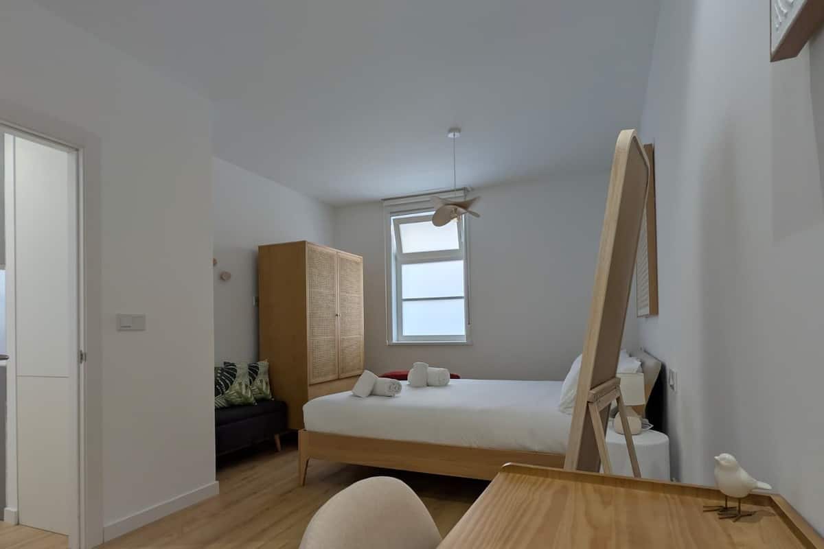 Une chambre à coucher avec un lit, un bureau, une armoire et une fenêtre.