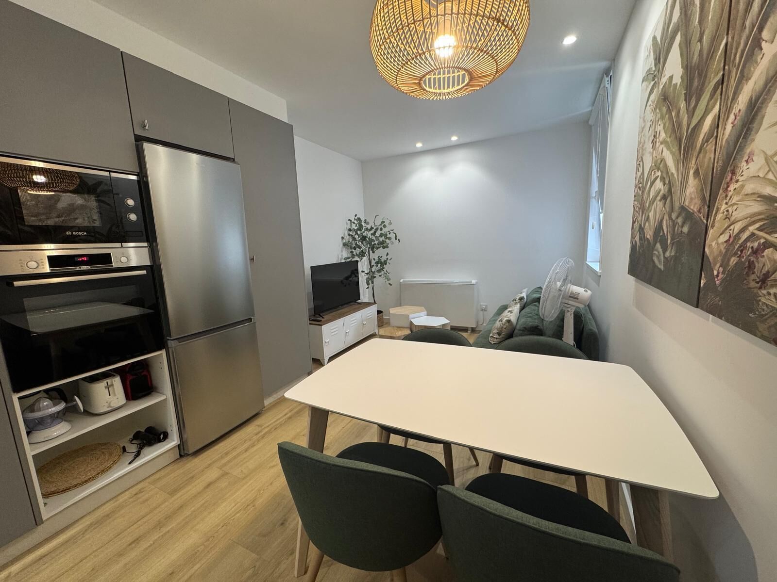 Una cocina moderna con horno empotrado, una mesa de comedor con sillas y una lámpara colgante.