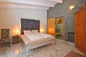 A bedroom with a bed, nightstand, chair, and a mirror.